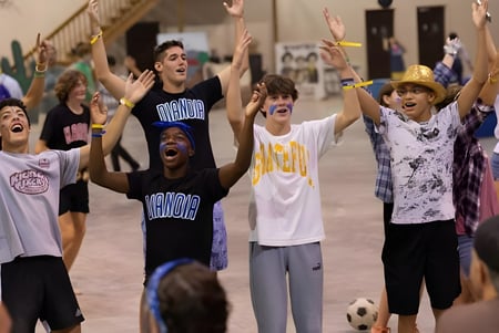 Un grupo de estudiantes de la Winston Salem Christian School celebra con los brazos en alto.