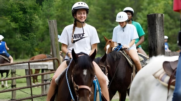 Dos personas montan con cascos en caballos en un área exterior cercada en el campus de la Winston Salem Christian School.