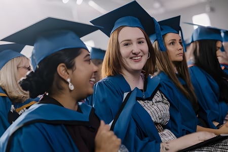 Un grupo de graduados en togas azules está en el pasillo de la Wollongong University.