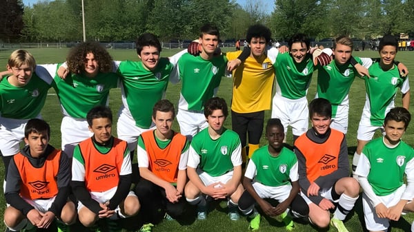 Un grupo de estudiantes del Woodbridge College está en camiseta de fútbol para una foto de equipo en el césped.