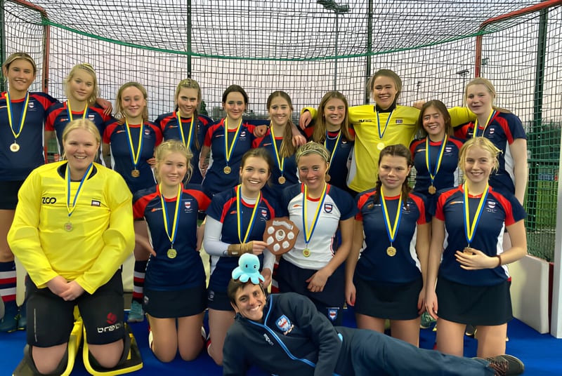 Un grupo de jóvenes atletas posan en un gimnasio de la Woodbridge School frente a una red y un poste de gol.