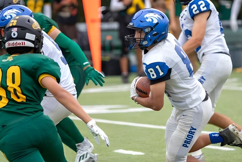 Dos jugadores de fútbol se enfrentan en el campo de la Woodside Priory School con más jugadores al fondo.