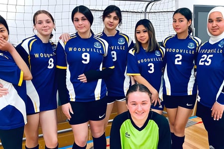 Un grupo de jóvenes jugadoras de voleibol de la Woodville High School posan juntas en la cancha de voleibol.