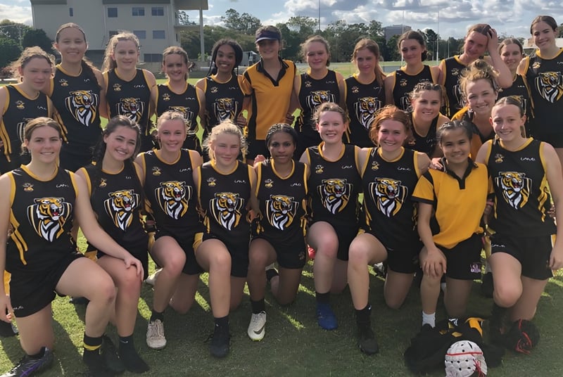 Un grupo de jóvenes atletas posan en uniforme deportivo en una pradera frente a un edificio en el campus de Worksop College.