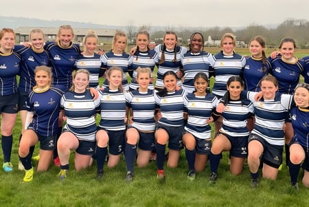 Un grupo de jóvenes futbolistas posa con uniformes en el campo de deportes de Worth School frente a un bosque.