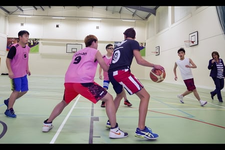 Estudiantes de la Worthgate School Canterbury juegan al baloncesto en el gimnasio.
