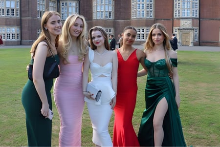 Un grupo de jóvenes estudiantes en ropa formal posan frente a un histórico edificio de ladrillo en el campus del Wrekin College.