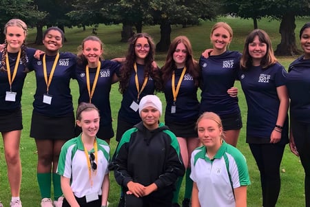 Un grupo de jóvenes alumnas de la Wychwood School está en uniforme deportivo en un campo al aire libre.