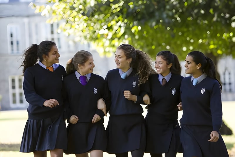 Un grupo de estudiantes femeninas está de pie y conversando en el campus de la Wycombe Abbey School.