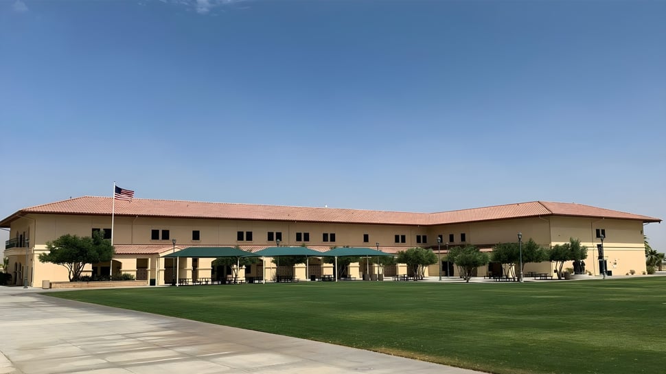 El edificio principal de dos pisos de Xavier College Preparatory High School se encuentra frente a un cielo azul claro con césped bien cuidado y palmeras.