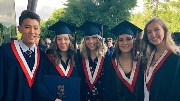 Un grupo de graduadas y graduados de la Yale Secondary School está al aire libre frente a árboles y áreas verdes.