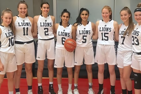 Un grupo de jugadoras de baloncesto de la Yale Secondary School están juntas y sostienen un balón de baloncesto.