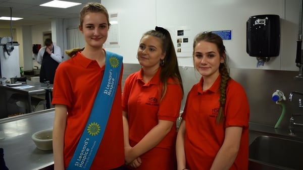 Tres estudiantes con uniformes rojos están en la cocina del campus del York College.